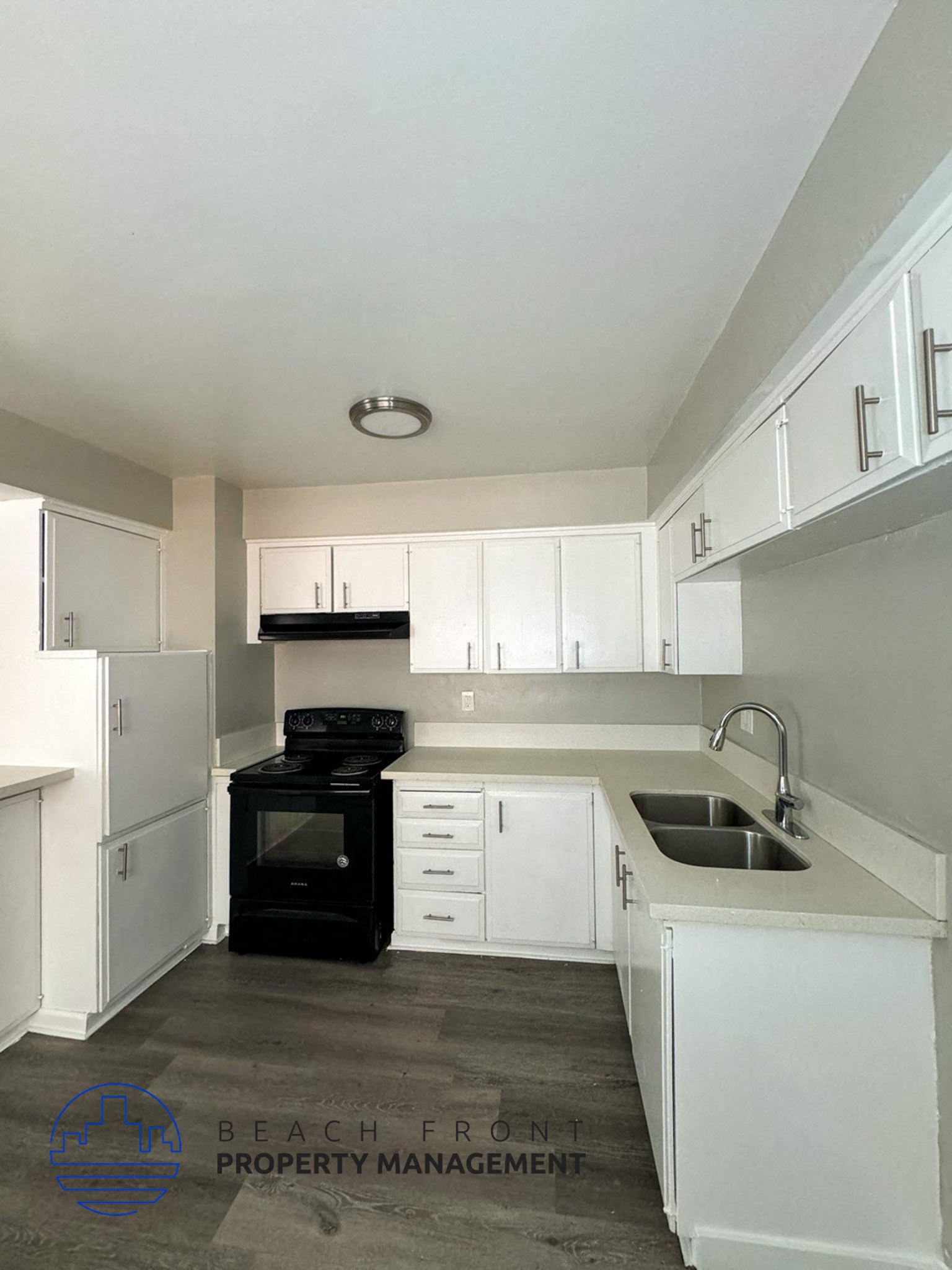 an empty kitchen with white cabinets and black appliances